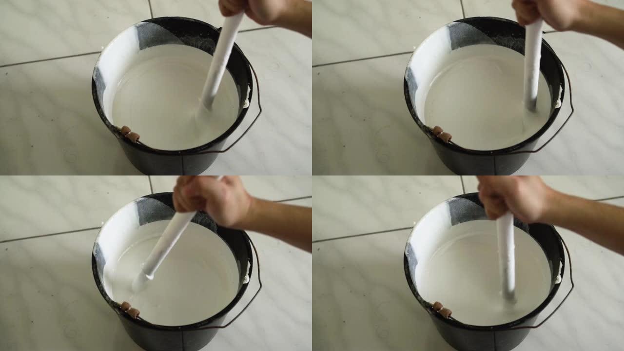 在桶上搅拌白色油漆，慢动作视频