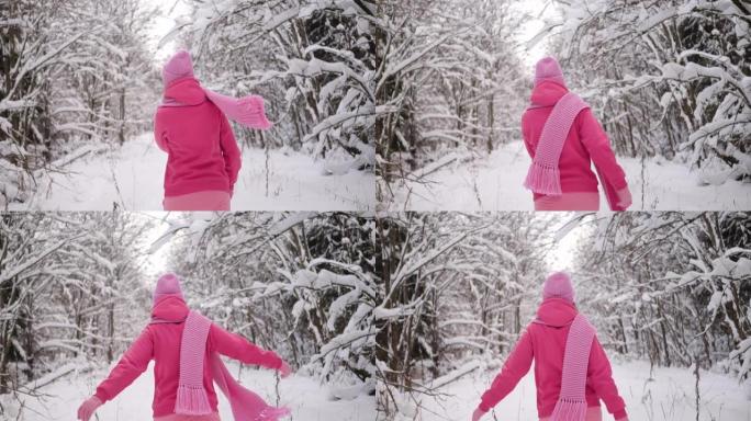 穿着粉红色衣服的女人戴着扎好的帽子和围巾穿过雪地