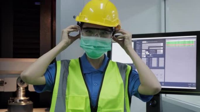 在工作场所或工厂工作前，亚洲女工/工程师佩戴处理面罩，以保护粉尘烟雾和电晕病毒。然后举起拇指表示自信