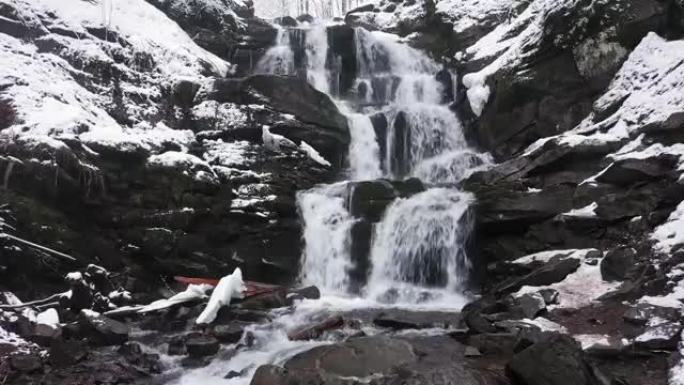 山区的冬季瀑布。水冲破冰雪