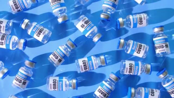 俯视图，玻璃小瓶新型冠状病毒肺炎疫苗在蓝色背景。一组冠状病毒的疫苗瓶。