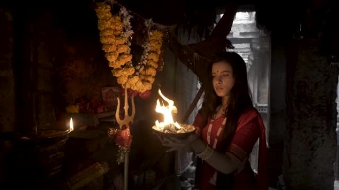 穿着旧stepwell的印度女孩穿着传统的印度红色纱丽，金色珠宝和手镯，手持火板