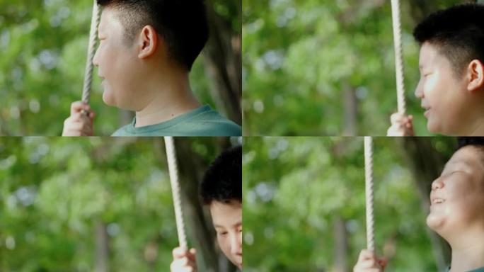 快乐的亚洲青春期男孩玩秋千，挂在公园户外的树上，生活方式的概念。