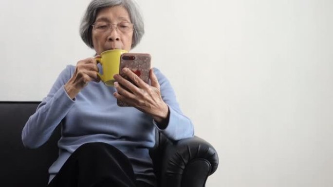 高级妇女喝咖啡并使用智能手机