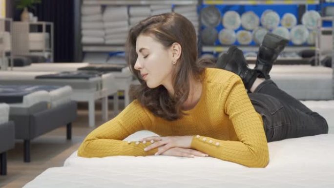 可爱的女人在家具商店尝试矫形床垫