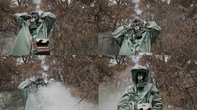 穿着老式危险品套装的男子戴上第二次世界大战的防毒面具，白色气体，蒸气或烟雾在森林中滚滚而来。原始视频