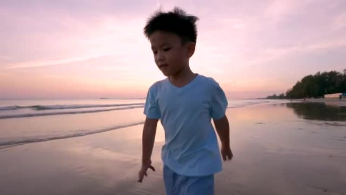 亚洲孩子在海滩上跑步。度假和健康的概念