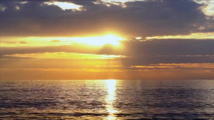 海面日出，阳光明亮，云彩和橙色暖光。橙色的天空，黄色的太阳和惊人的云景。夏日日落海景，波澜不惊。海洋