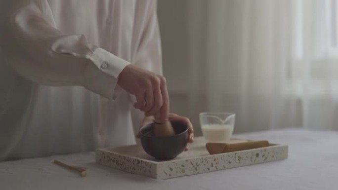 传统茶制作: 一位匿名妇女的手将抹茶粉压入杯子中