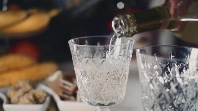 香槟从瓶子里倒进玻璃杯里。玻璃上方可见气泡。特写镜头