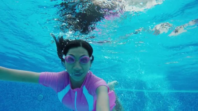 快乐的亚洲女孩和家人一起在游泳池游泳，在水下射击。
