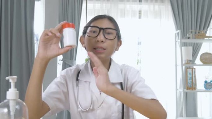 亚洲药剂师女孩在家通过视频通话解释药瓶，锁定生活方式概念。