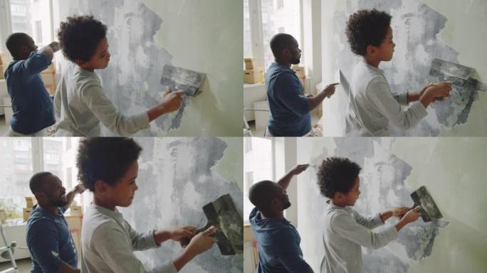 黑人男子在小儿子的帮助下刮墙