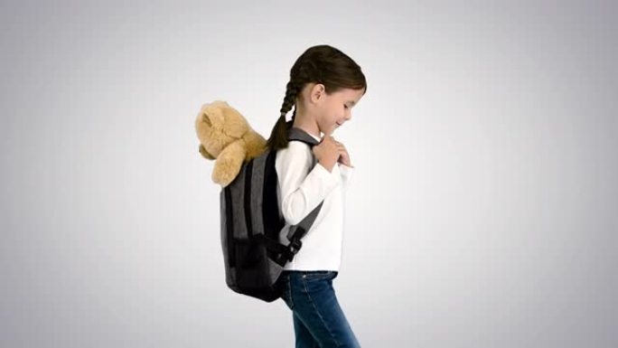 Cute little girl walking to school with a teddy be