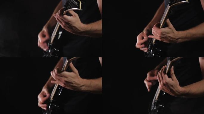 穿着黑色衣服的无法识别的摇滚音乐家在黑色背景上演奏黑色电吉他，与世隔绝。
