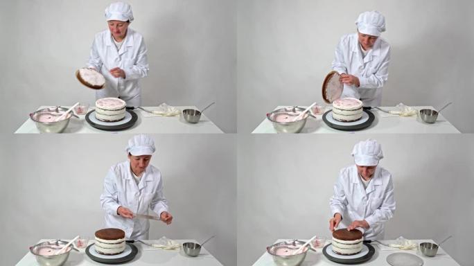 一位穿着白色长袍的面包师妇女将蛋糕的最后一层放在糖奶油上。烘焙用糖果。