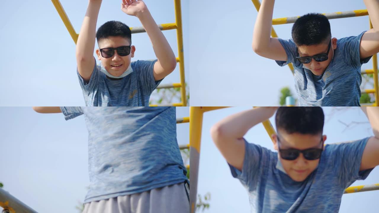 快乐的亚洲男孩在阳光明媚的日子里戴着墨镜在操场上玩耍，生活方式理念。