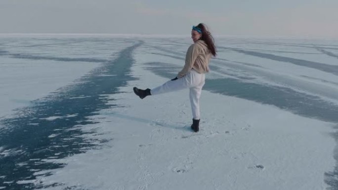 时尚的年轻女子，专业的舞者，在寒冷的冬天在冰冻的湖上跳舞充满活力的爵士放克或嘻哈。在冰雪覆盖的冰冻北
