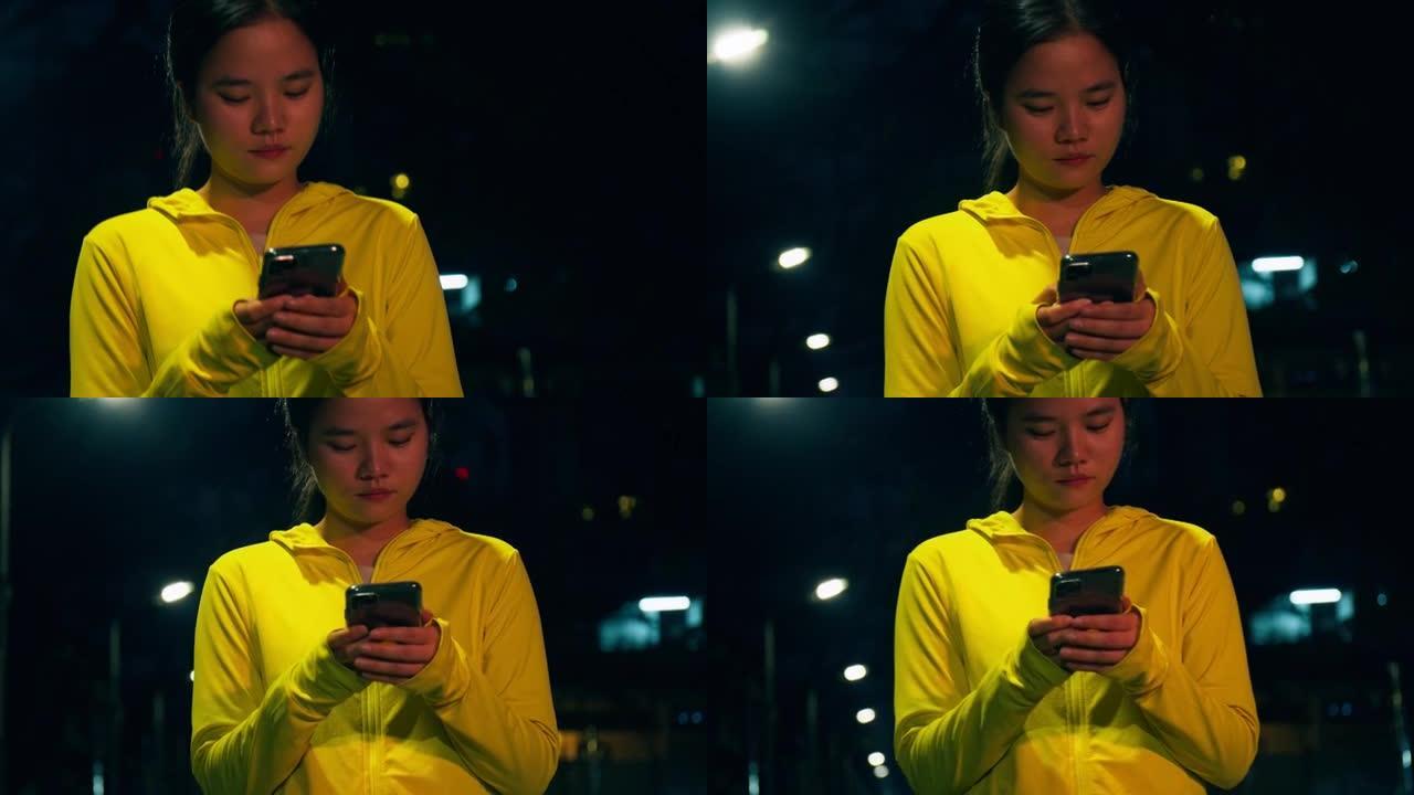 晚上在市区进行锻炼训练后，女运动员使用智能手机。