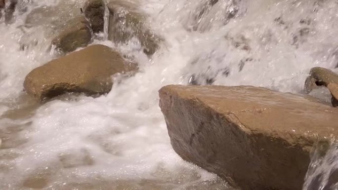 暴风雨的河水冲刷着大石头，喷雾和泡沫在飞舞。慢动作视频