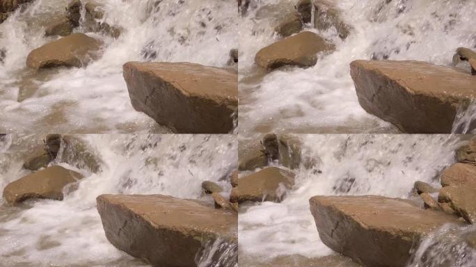 暴风雨的河水冲刷着大石头，喷雾和泡沫在飞舞。慢动作视频