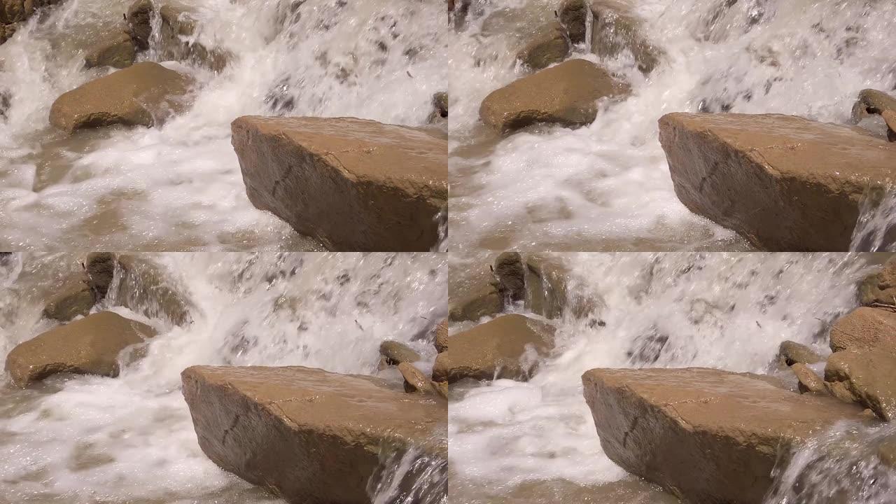 暴风雨的河水冲刷着大石头，喷雾和泡沫在飞舞。慢动作视频