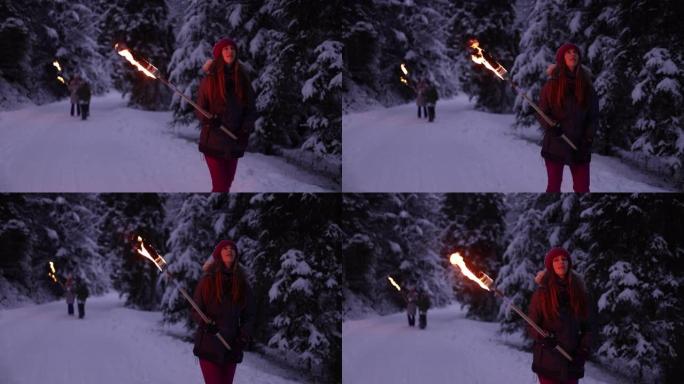 十几岁的女孩和她的家人带着火炬在冬季森林中行走