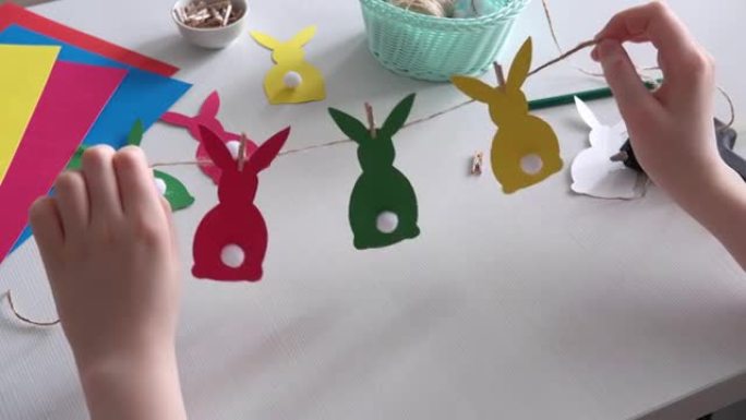 男孩做了复活节纸花环。彩色复活节兔子由纸和绒球制成，并配有衣夹。