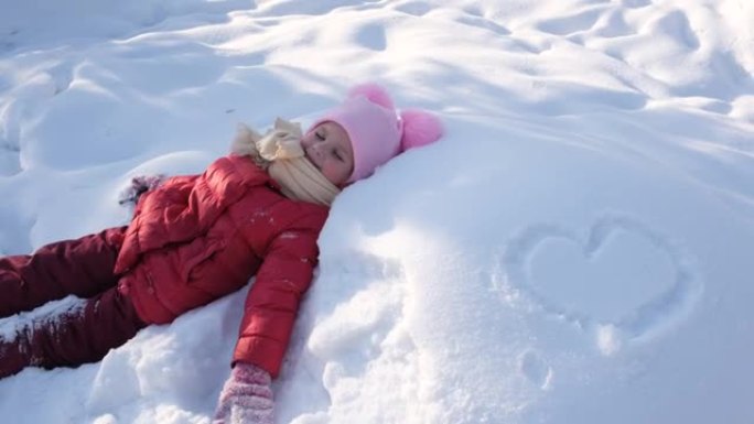 冬天在公园玩耍的孩子躺在雪堆里玩得开心，冬天在户外活动游戏