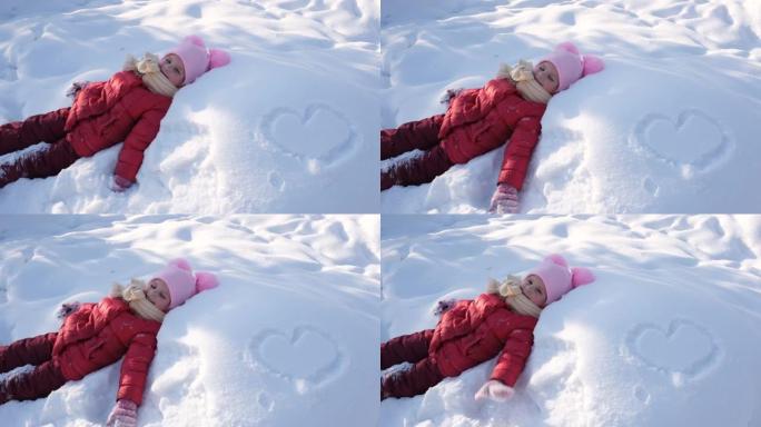 冬天在公园玩耍的孩子躺在雪堆里玩得开心，冬天在户外活动游戏