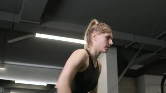 一个年轻漂亮的女人在黑暗的健身房里使用手操机器。