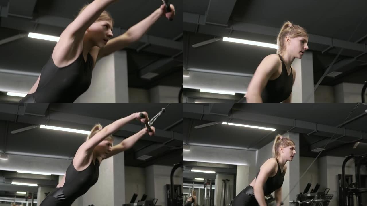 一个年轻漂亮的女人在黑暗的健身房里使用手操机器。