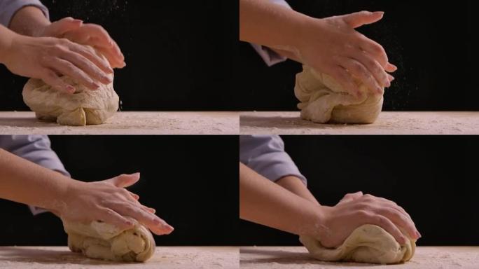 女人的手在桌子上揉面粉。用面粉制作手工面团的过程。制作面包、烹饪烘焙和糖果。特写，慢动作