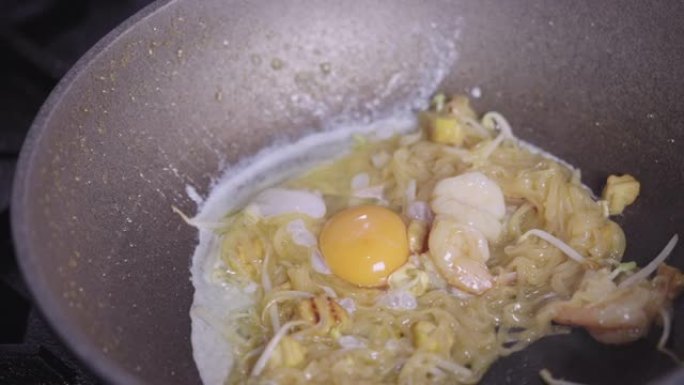 SLO MO: 烹饪泰式或炒面时，人手将鸡蛋放入。