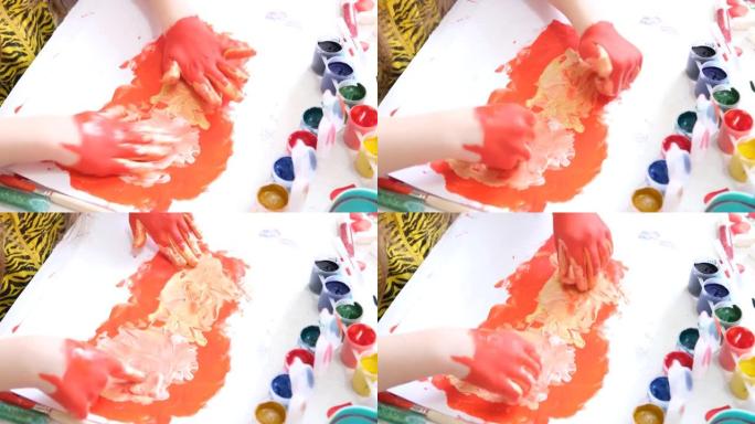 小女孩玩得开心，画她的手。有趣的孩子用红色油漆画脏手。
