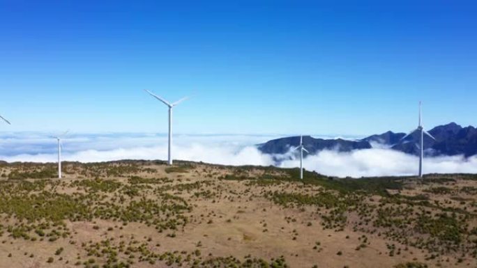 4k风力发电机在荒芜的农村地区云层和背景中的山脉中旋转。无人机镜头，无人机飞越田野上升。
