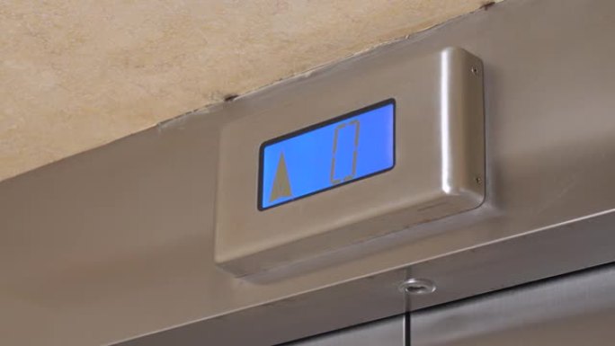 金属面板上带有箭头的蓝屏显示了高层建筑中现代电梯的提升，近距离拍摄。