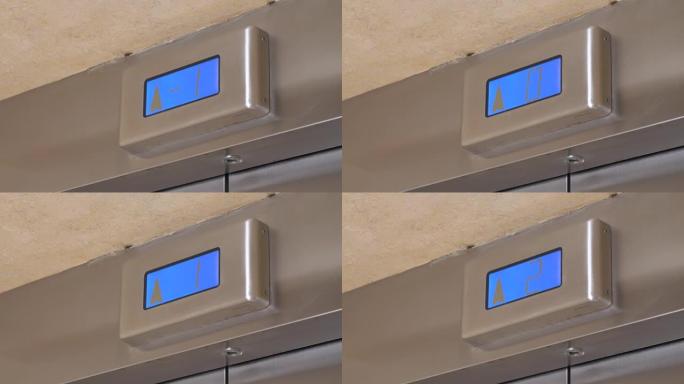 金属面板上带有箭头的蓝屏显示了高层建筑中现代电梯的提升，近距离拍摄。