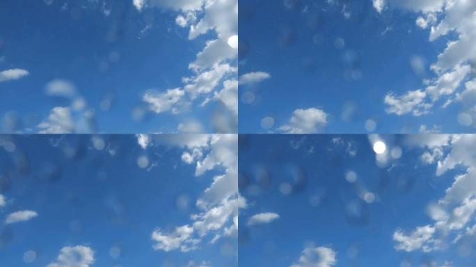 晴天从蓝天落下的雨。雨滴落在相机镜头上。低角度拍摄200 fps慢动作
