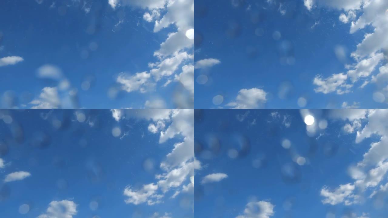 晴天从蓝天落下的雨。雨滴落在相机镜头上。低角度拍摄200 fps慢动作