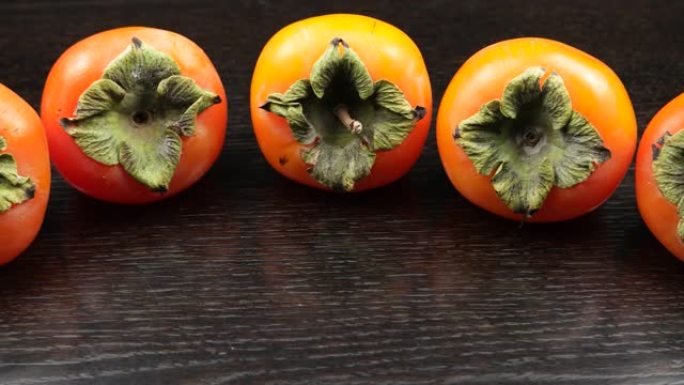 成熟的柿子水果排成一排在黑色的木桌上，