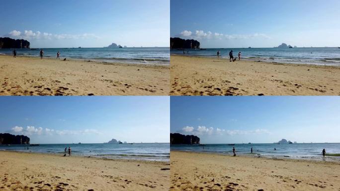 泰国甲米奥南海滩镇美丽的海滩，展现了人们在金色沙滩上漫步，在海洋中玩乐的场景。