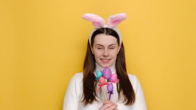 20岁微笑的年轻女孩的肖像在粉红色的兔子蓬松的耳朵里，建议拿复活节彩蛋，手中有象征性的东西，穿着白色