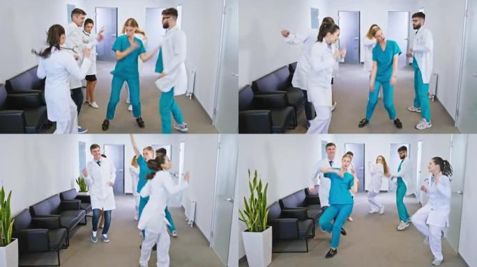 一群年轻成熟的医生和护士在现代医院走廊的镜头前兴奋地跳舞