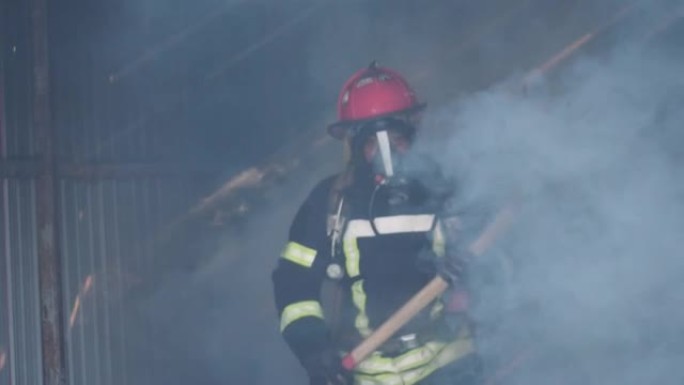 亚洲消防员走路自信地拿着斧头燃烧着浓烟火烧得很厉害