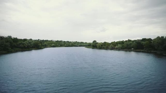 河上的日落。鱼跳出水面。岸边有绿树的平静湖的风景。