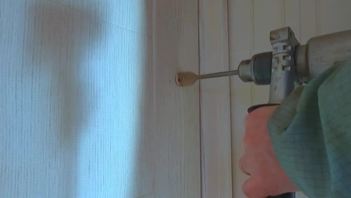 一名工人用钻头在门上开一个锁孔