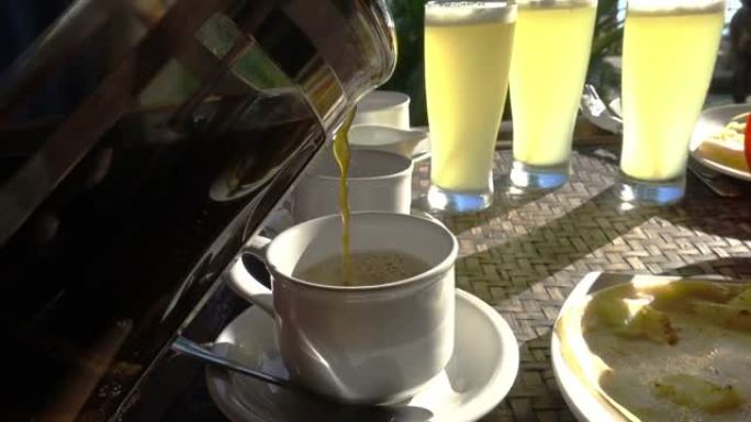 咖啡和牛奶洒在杯子里，背景是喝果汁，在热带度假胜地吃早餐