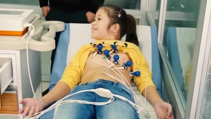 带有心电图传感器的快乐年轻女孩躺在沙发上。儿童心电图。