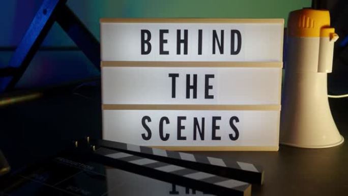 幕后在演播室变色背景灯灯箱上的信板文字。电影灯箱旁边的电影石板隔板扩音器和导演椅。视频制作电影概念。